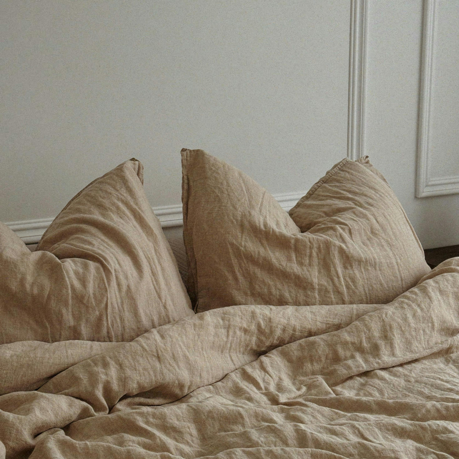 Photo of a made up bed, soft yellow bedding and pillows.